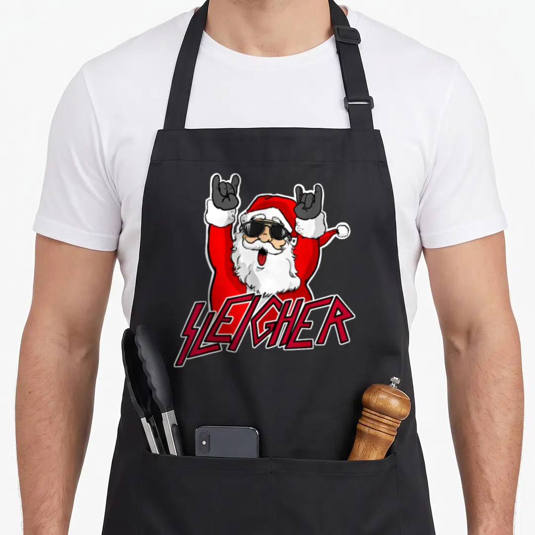 Metal santa claus apron - Cartoon Santa with sunglasses making rock horns above SLEIGHER text in red and black — shown on a black cotton canvas apron against a white background