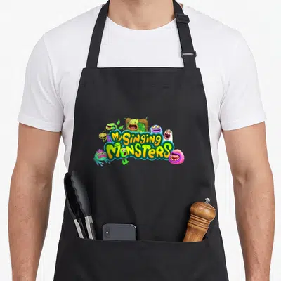 Plush boy monster apron - My Singing Monsters logo with yellow green blue and pink cartoon creatures — shown on a black cotton canvas apron against a white background