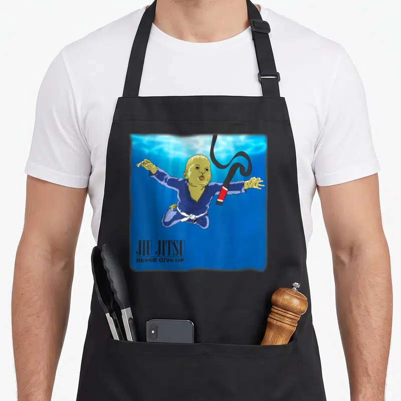 Bjj youll never apron - Cartoon baby in blue gi floating underwater with swirling black belt and text — shown on a black cotton canvas apron against a white background