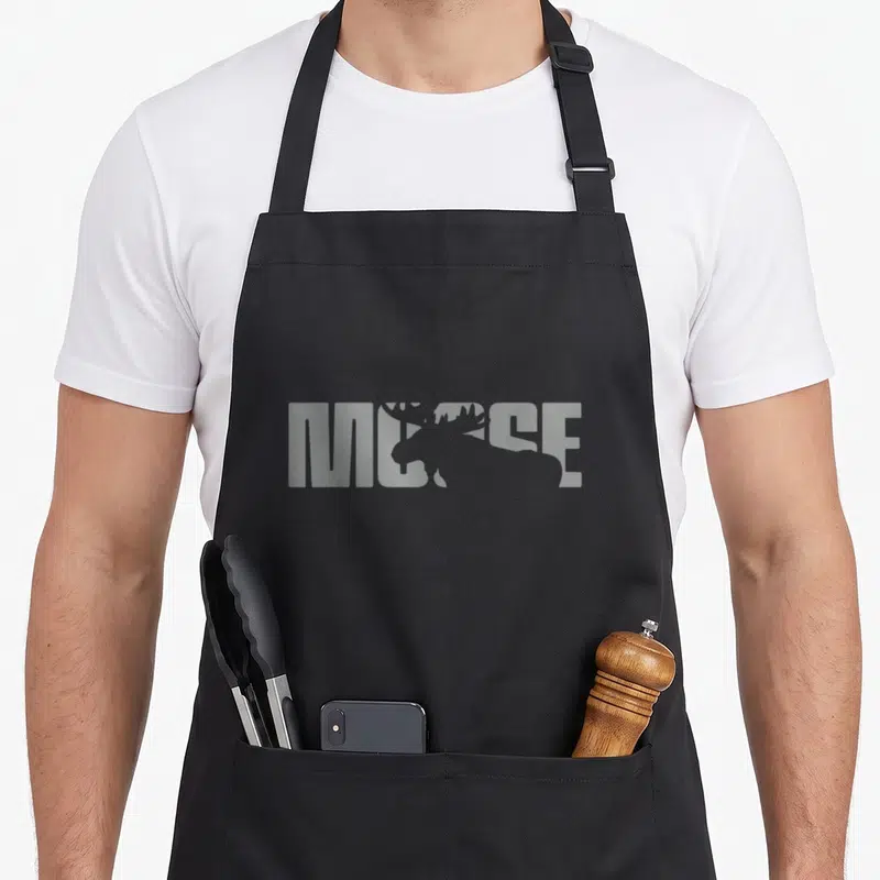 Vintage moose apron - Grey moose silhouette overlapping the word MOOSE in block letters — shown on a black cotton canvas apron against a white background