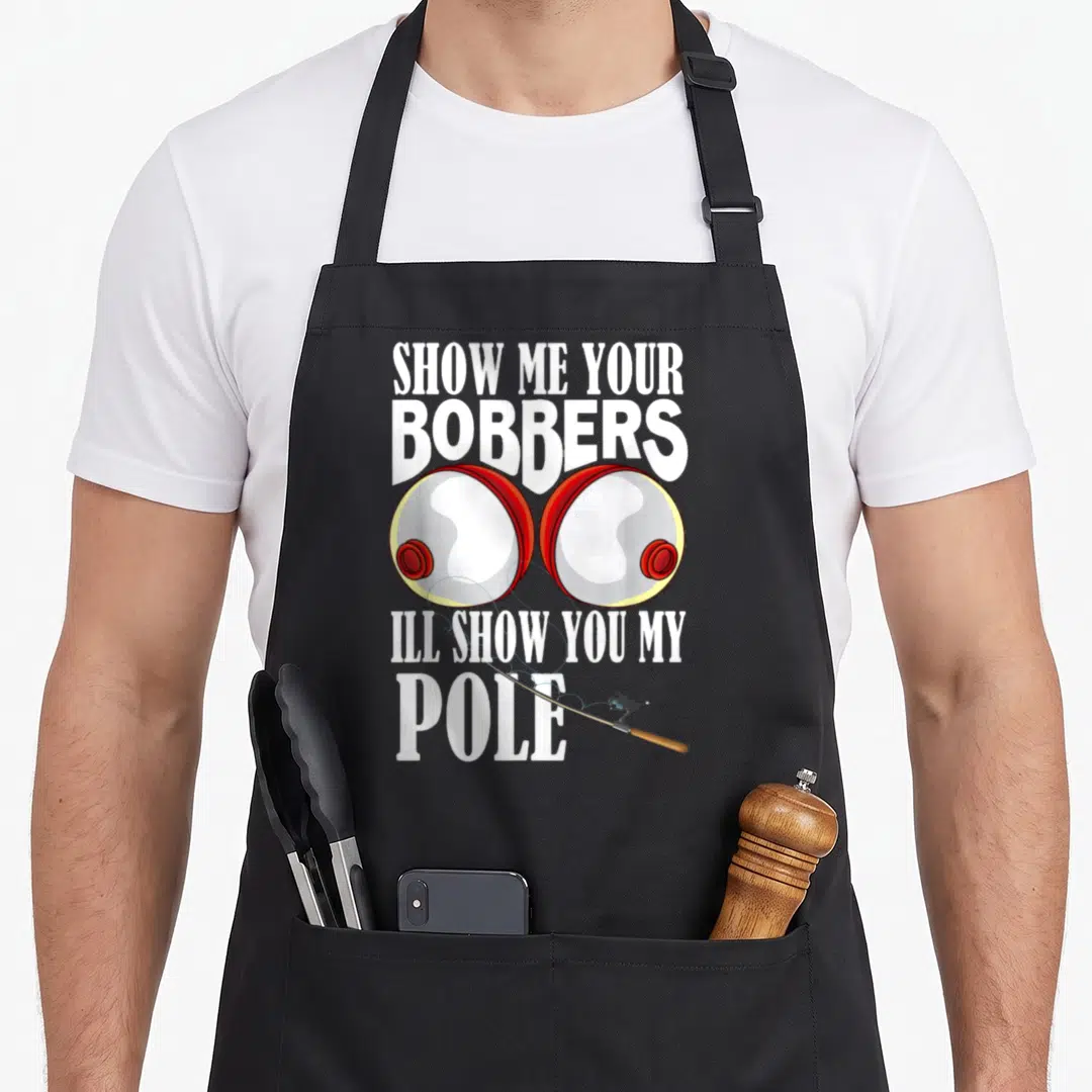 Show carp apron - Two red and grey cartoon bobbers with white pun text and diagonal fishing pole — shown on a black cotton canvas apron against a white background