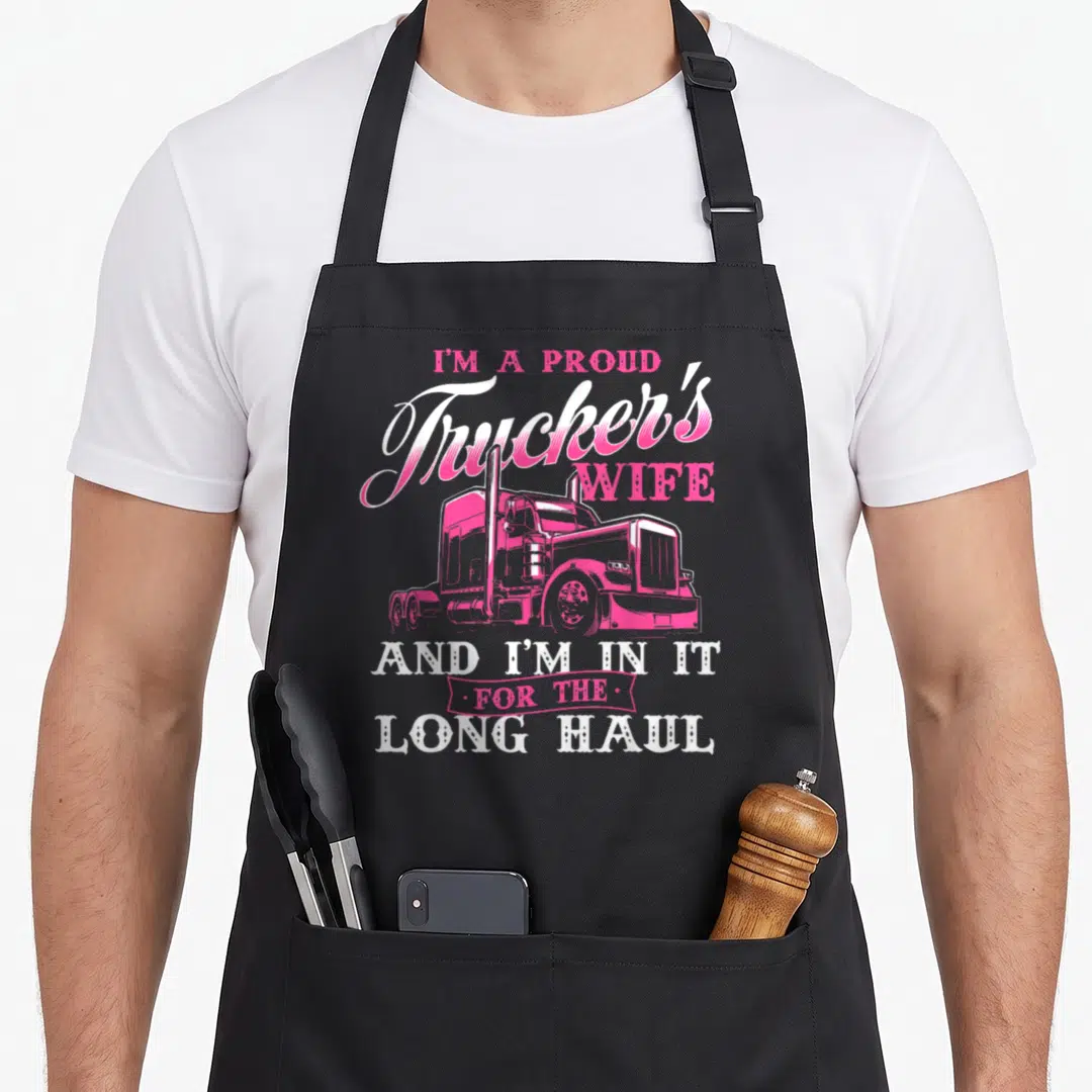 Proud semi truck apron - Pink semi-truck illustration surrounded by stacked white and pink text reading I'm A Proud — shown on a black cotton canvas apron against a white background
