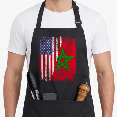 Morocco american flag apron - Two distressed flags merged with torn edge in red white blue and green — shown on a black cotton canvas apron against a white background