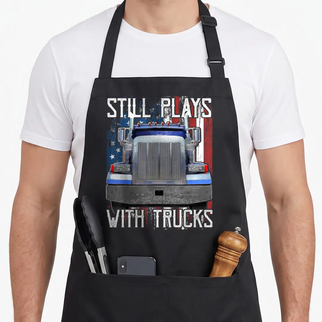 Play american flag apron - Frontal semi-truck graphic on distressed red white and blue flag with white text — shown on a black cotton canvas apron against a white background