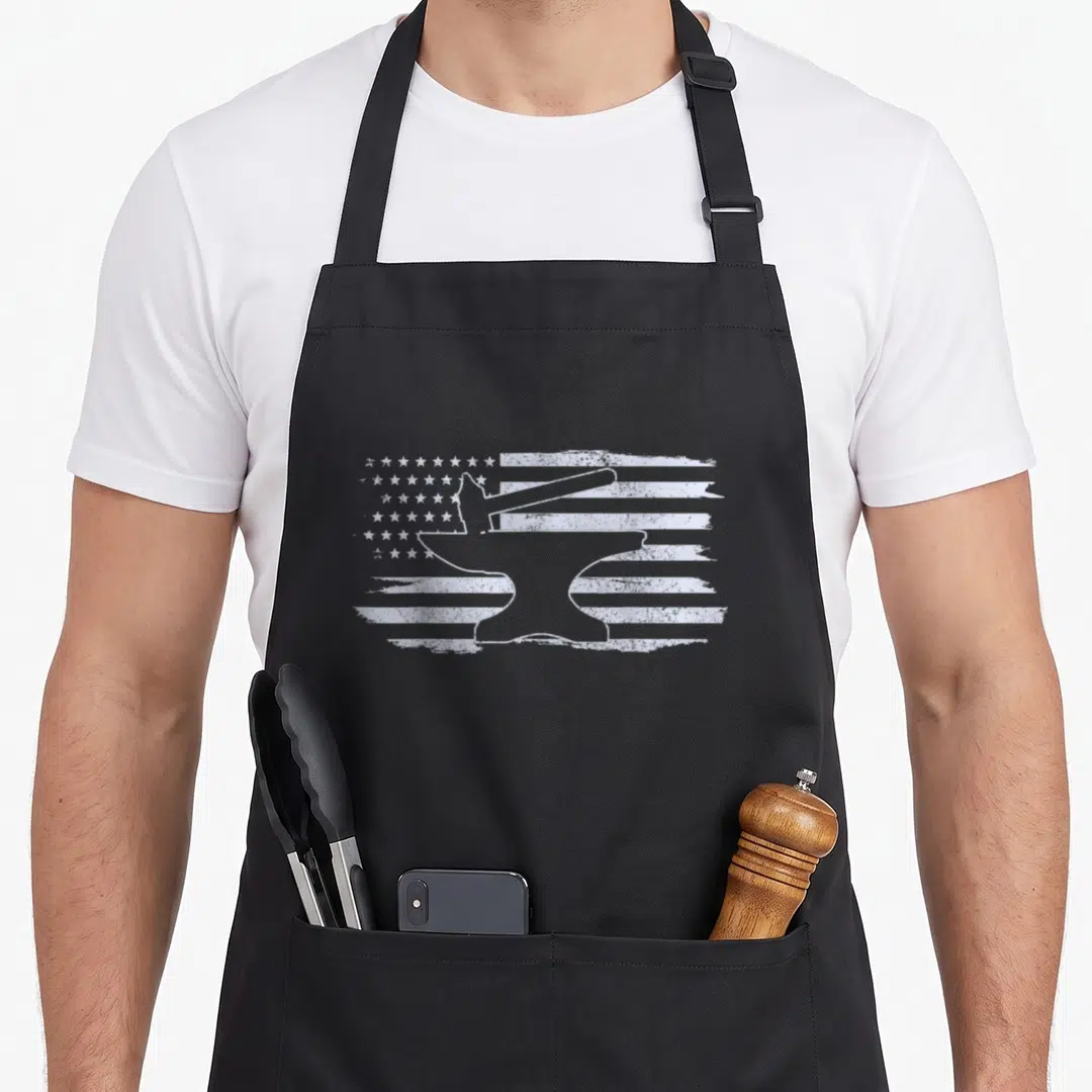 Hammer blacksmith apron - White anvil and hammer silhouette over distressed American flag pattern on dark fabric — shown on a black cotton canvas apron against a white background