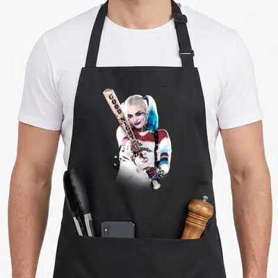 Suicide squad bat apron - Harley Quinn holding a wooden bat with GOOD NIGHT text in blue, red, white, and beige — shown on a black cotton canvas apron against a white background