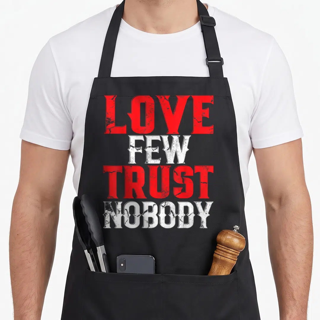 Few urban apron - Red and white distressed text reading LOVE FEW TRUST NOBODY stacked vertically — shown on a black cotton canvas apron against a white background