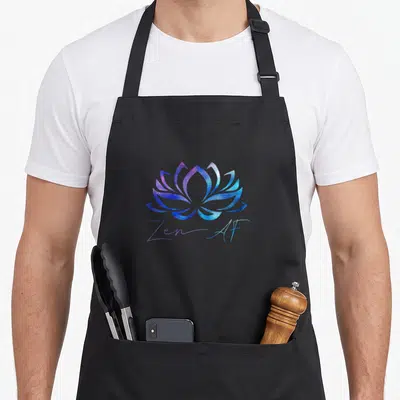 Zen funny passion apron - Galaxy textured lotus flower in purple and blue above handwritten Zen-AF text — shown on a black cotton canvas apron against a white background