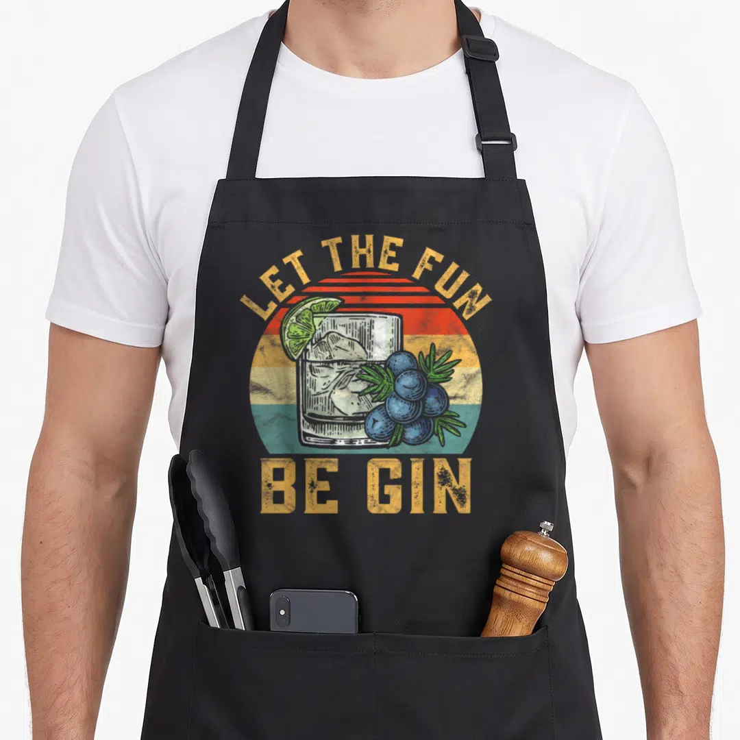 Tonic gin apron - Retro glass of gin with lime, berries, and striped sun background with yellow text — shown on a black cotton canvas apron against a white background
