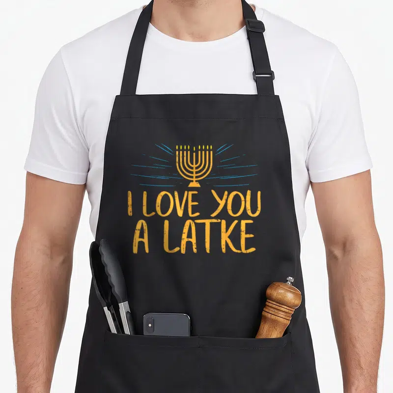 Latke hanukkah apron - Orange menorah with blue rays above stacked text reading I LOVE YOU A LATKE — shown on a black cotton canvas apron against a white background