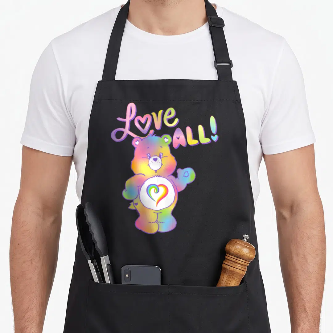 Togetherness care apron - Rainbow bear with heart belly badge and Love ALL! text in cartoon style — shown on a black cotton canvas apron against a white background