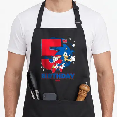 Epic birthday apron - Leaping blue hedgehog in front of red number 5 with TH BIRTHDAY text — shown on a black cotton canvas apron against a white background