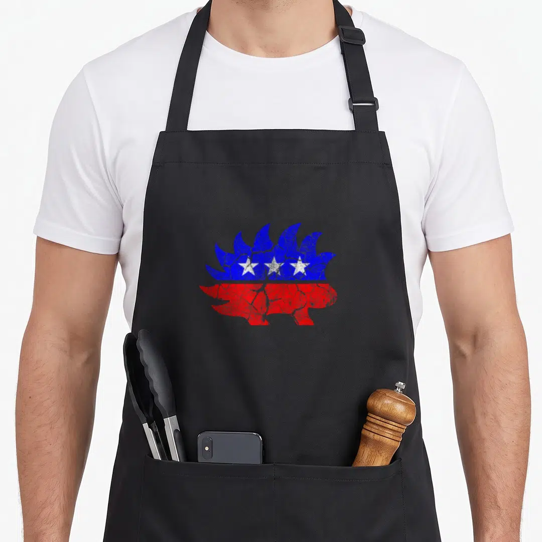 Freedom porcupine apron - Distressed hedgehog silhouette in blue and red with three white stars — shown on a black cotton canvas apron against a white background