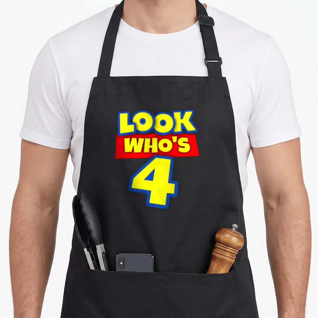 Cute theme birthday apron - Yellow text reading Look Who's 4 with blue outline over red banner — shown on a black cotton canvas apron against a white background