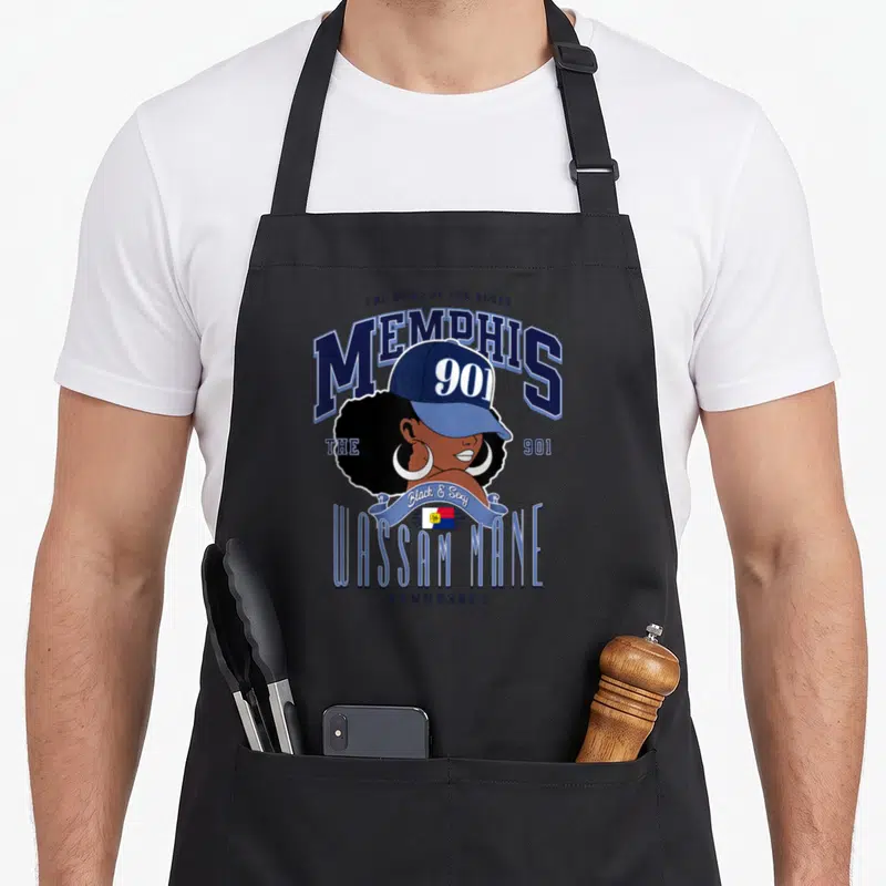 Hometown memphis apron - Cartoon woman with afro and 901 cap surrounded by Memphis text and Wassam Mane ribbon in blue — shown on a black cotton canvas apron against a white background