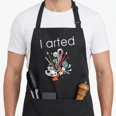 Arted colored aprons - I arted text above cartoon art supplies and colorful swirls — shown on a black cotton canvas apron against a white background