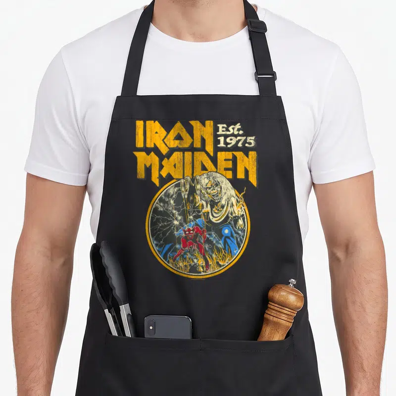 Beast camping apron - Distressed Iron Maiden text above zombie and red demon inside yellow circle with lightning — shown on a black cotton canvas apron against a white background