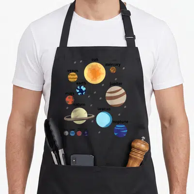 System planets galaxy men women kids apron - Solar system diagram with sun planets and dwarf planets labeled in blue — shown on a black cotton canvas apron against a white background