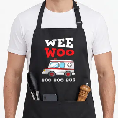 Driver ambulance girl apron - Cartoon ambulance with WEE WOO and BOO BOO BUS text in white and red — shown on a black cotton canvas apron against a white background