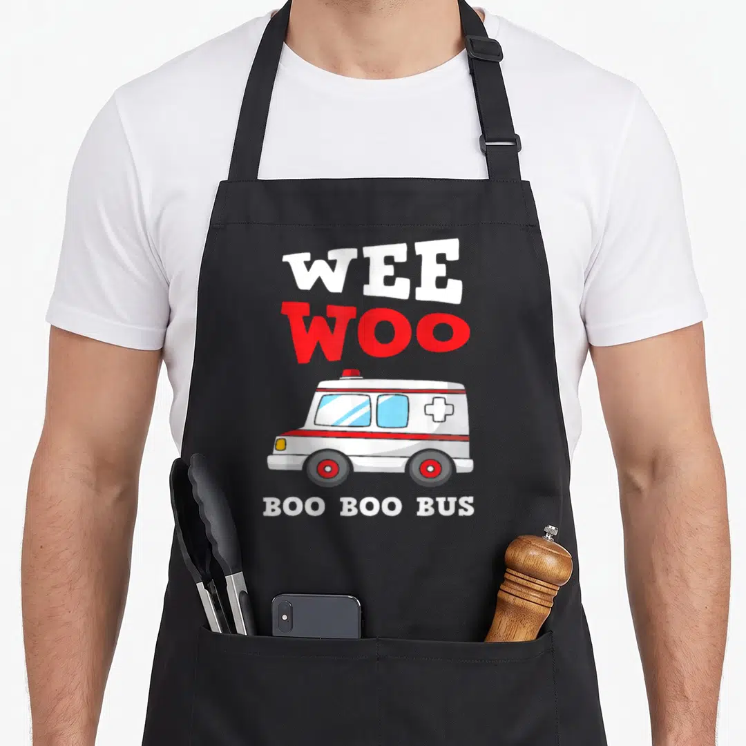Driver ambulance girl apron - Cartoon ambulance with WEE WOO and BOO BOO BUS text in white and red — shown on a black cotton canvas apron against a white background
