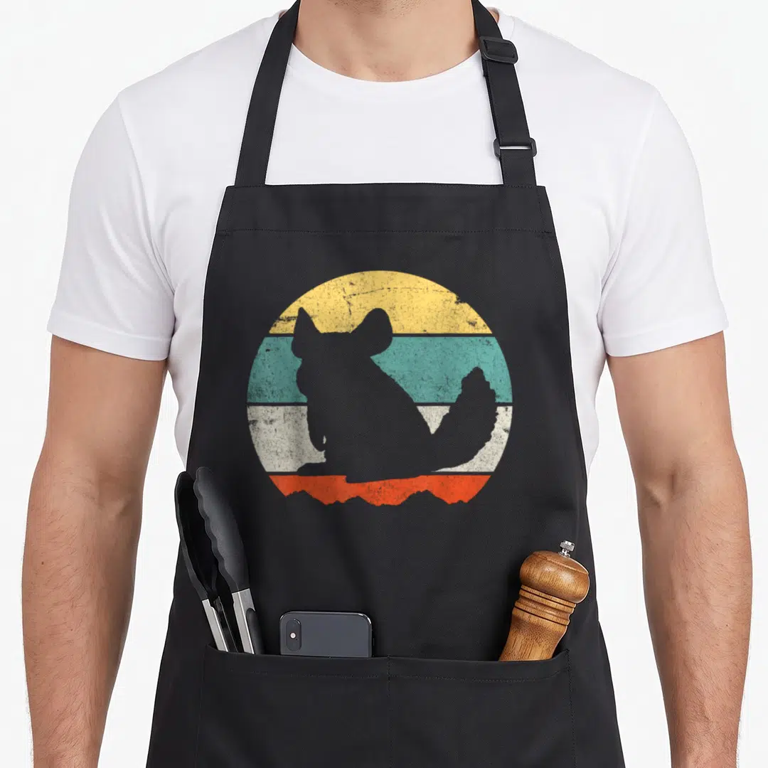 Funny chinchilla lover apron - Grey dog silhouette over yellow teal white and orange striped circle — shown on a black cotton canvas apron against a white background