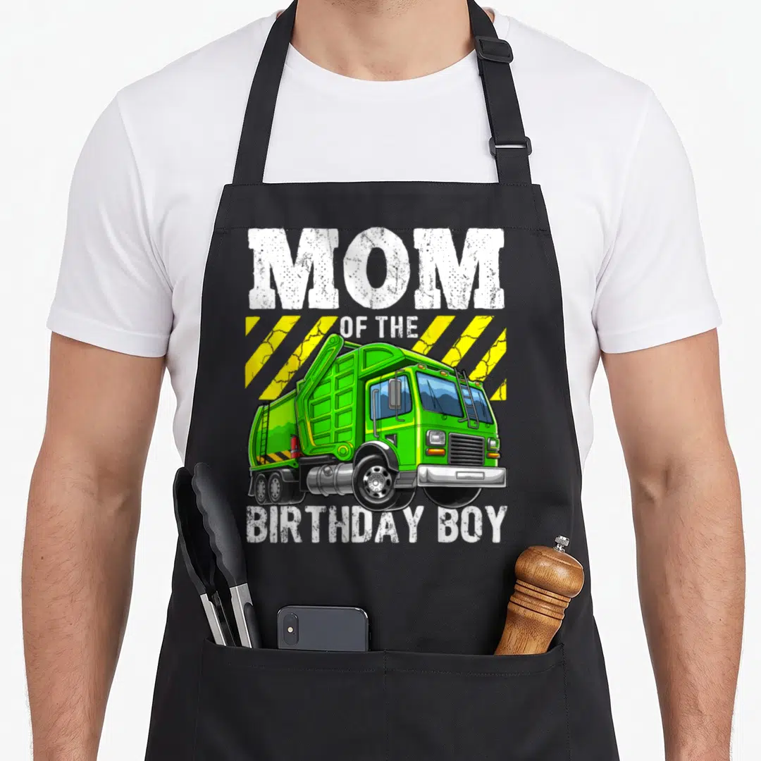 Funny birthday garbage truck apron - Green cartoon garbage truck with mom of the birthday boy text and yellow stripes — shown on a black cotton canvas apron against a white background
