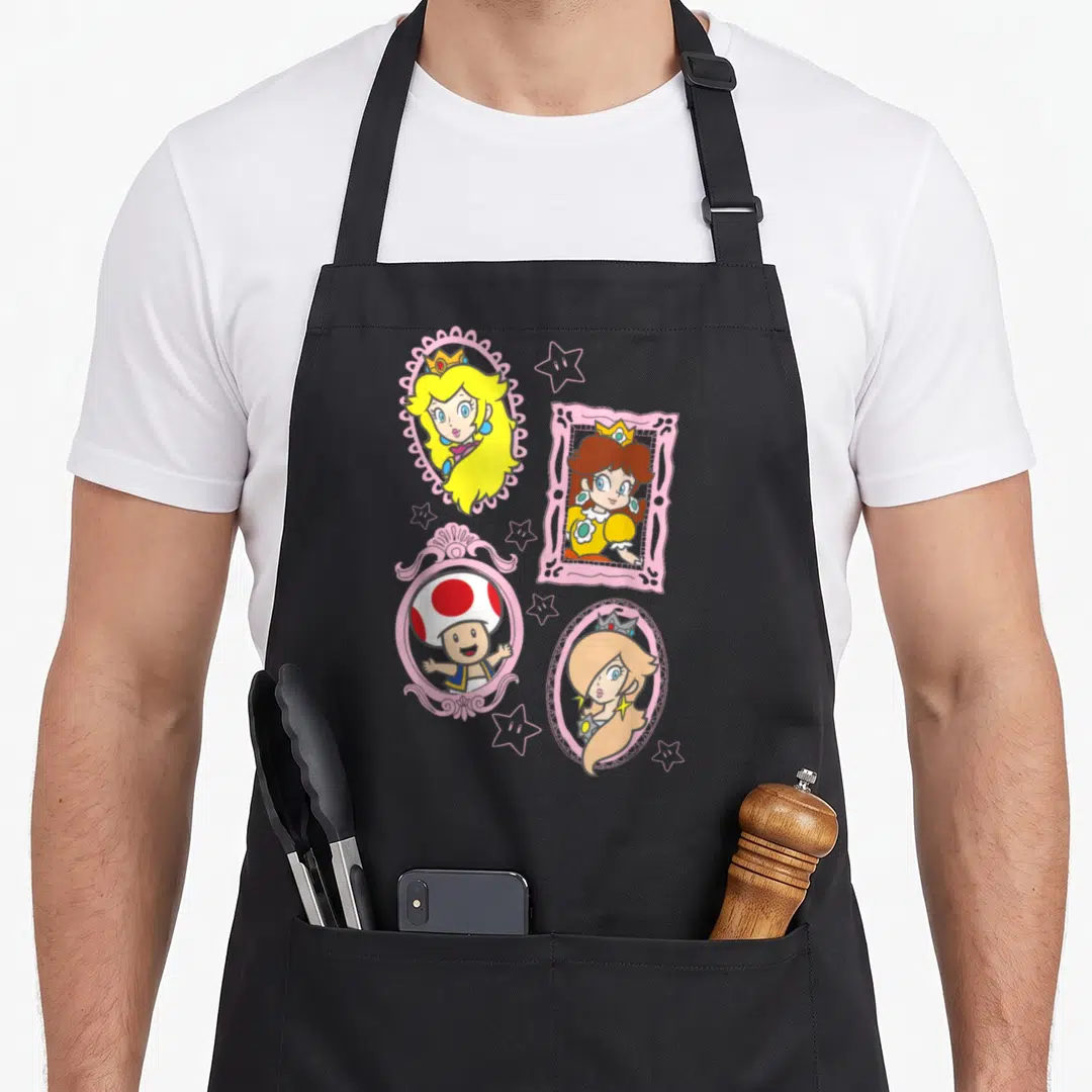 Toad princess apron - Four cartoon characters in pink frames with stars including Princess Peach, Daisy, Rosalina — shown on a black cotton canvas apron against a white background