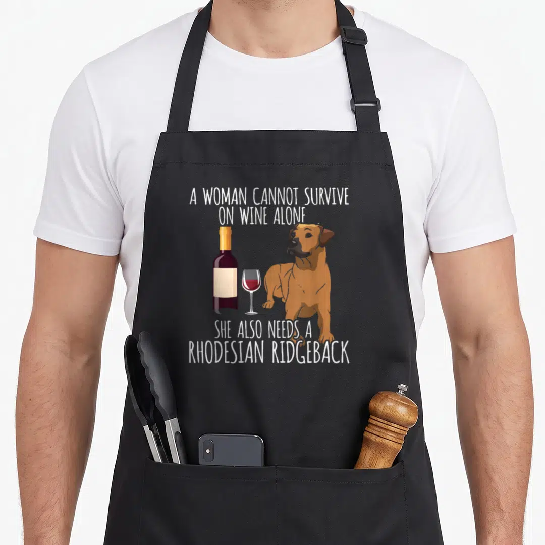 Rhodesian wine apron - Cartoon Rhodesian Ridgeback next to a wine bottle and glass with white text on grey background — shown on a black cotton canvas apron against a white background