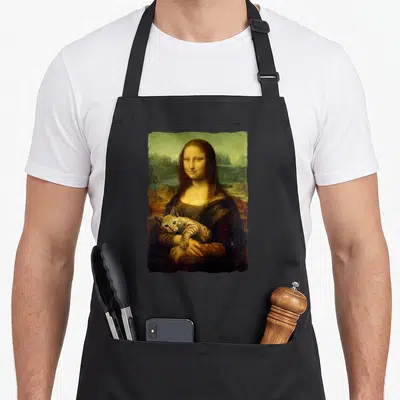 Mona kitty cat apron - Woman holding a striped tabby cat in a landscape painting style using brown, green, and tan — shown on a black cotton canvas apron against a white background