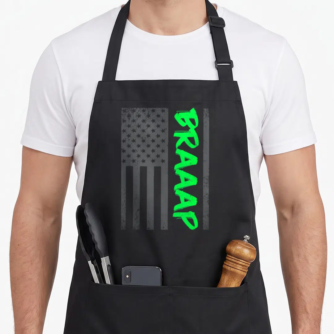 Brap bike apron - Vertical green BRAAAP text over grey distressed USA flag pattern — shown on a black cotton canvas apron against a white background