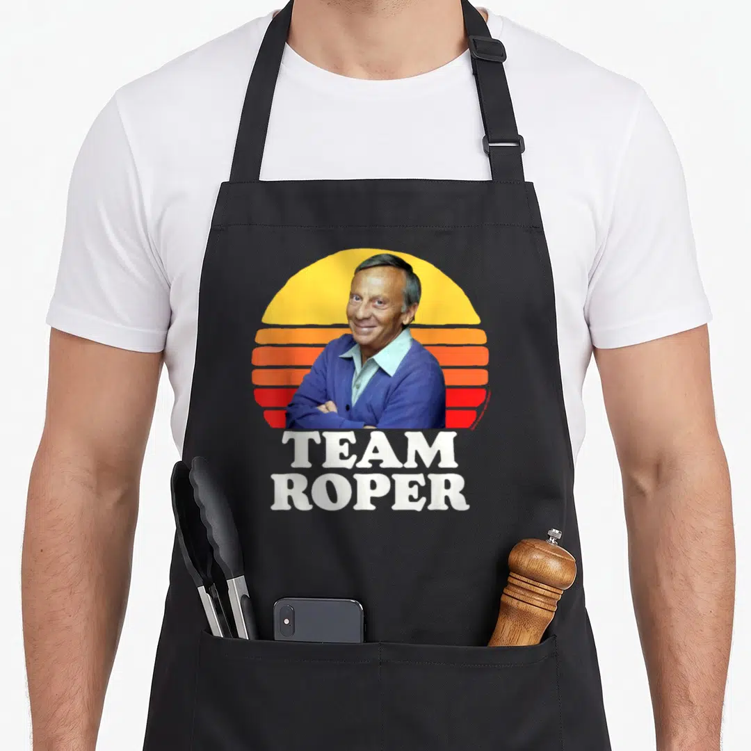 Helen mrs apron - Man portrait in front of yellow orange red striped sun with TEAM ROPER text below — shown on a black cotton canvas apron against a white background