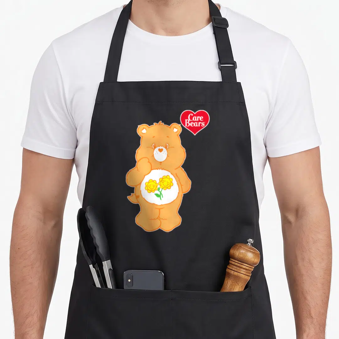 Friends apron for women - Orange bear with two yellow flowers and red Care Bears heart logo — shown on a black cotton canvas apron against a white background