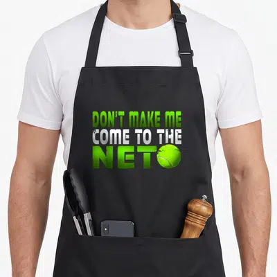 Come tennis apron - Green and white text reading Don't Make Me Come To The Net with a tennis ball replacing the O in NET — shown on a black cotton canvas apron against a white background