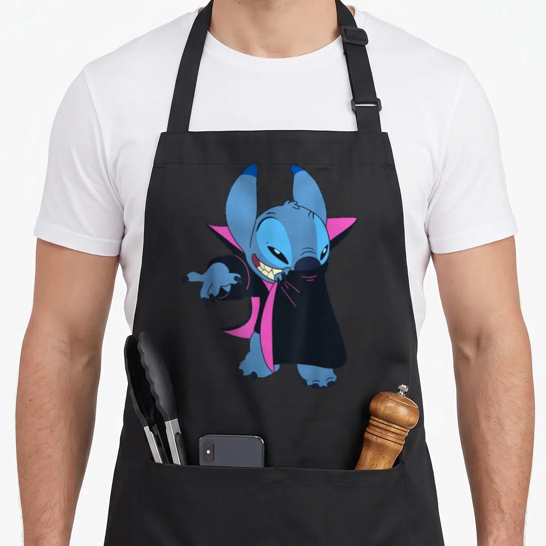 Stitch vampire halloween apron - Blue cartoon Stitch wearing a black cape with pink lining in a vampire pose — shown on a black cotton canvas apron against a white background