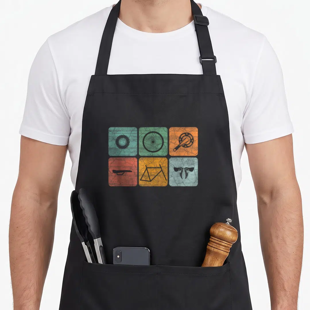 Biking cycling apron - Six colored squares with grey bicycle part silhouettes in a grid — shown on a black cotton canvas apron against a white background