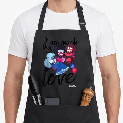 Steven love jay apron - Cartoon gems hugging with text I am made OF love above and below in black script — shown on a black cotton canvas apron against a white background