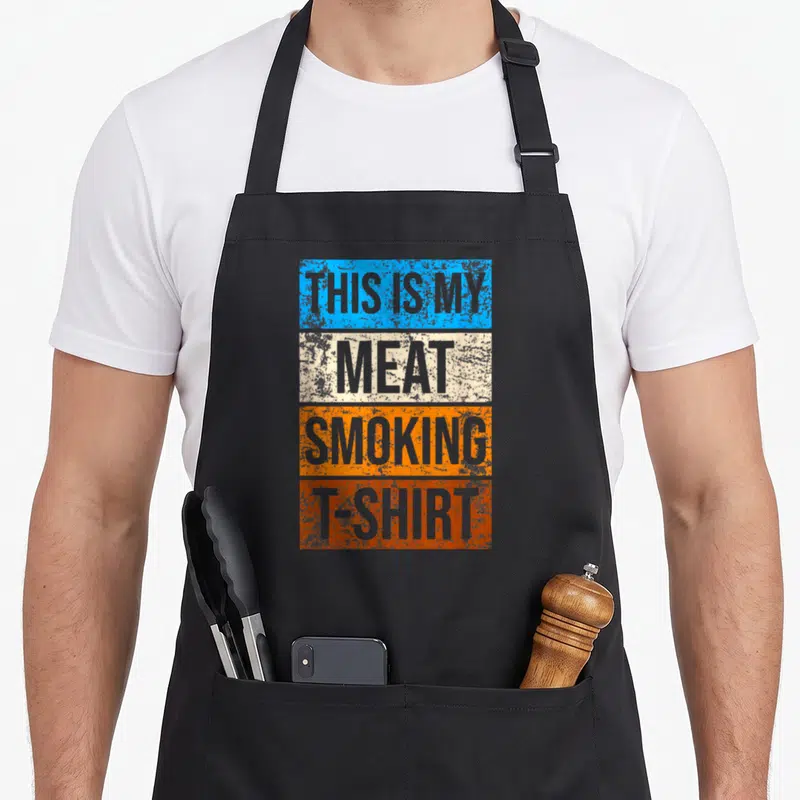 Funny meat smoking apron - Four stacked colored rectangles with grey distressed text reading THIS IS MY MEAT SMOKING — shown on a black cotton canvas apron against a white background