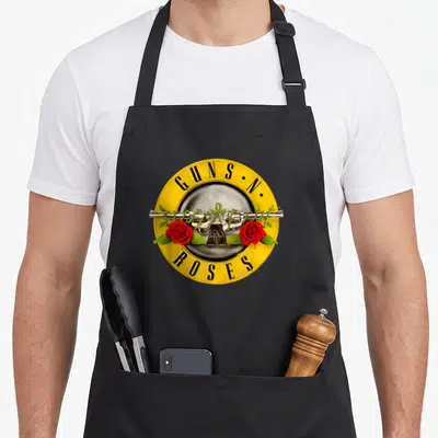 Bullet gun apron - Crossed silver revolvers with red roses and GUNS N•, ROSES text in yellow circle — shown on a black cotton canvas apron against a white background