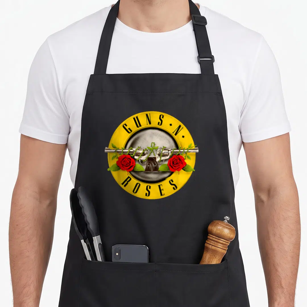 Bullet gun apron - Crossed silver revolvers with red roses and GUNS N•, ROSES text in yellow circle — shown on a black cotton canvas apron against a white background