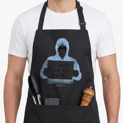 Mean better good apron - Line art of person in blue hoodie holding sign reading She Doesn't Even Go Here — shown on a black cotton canvas apron against a white background