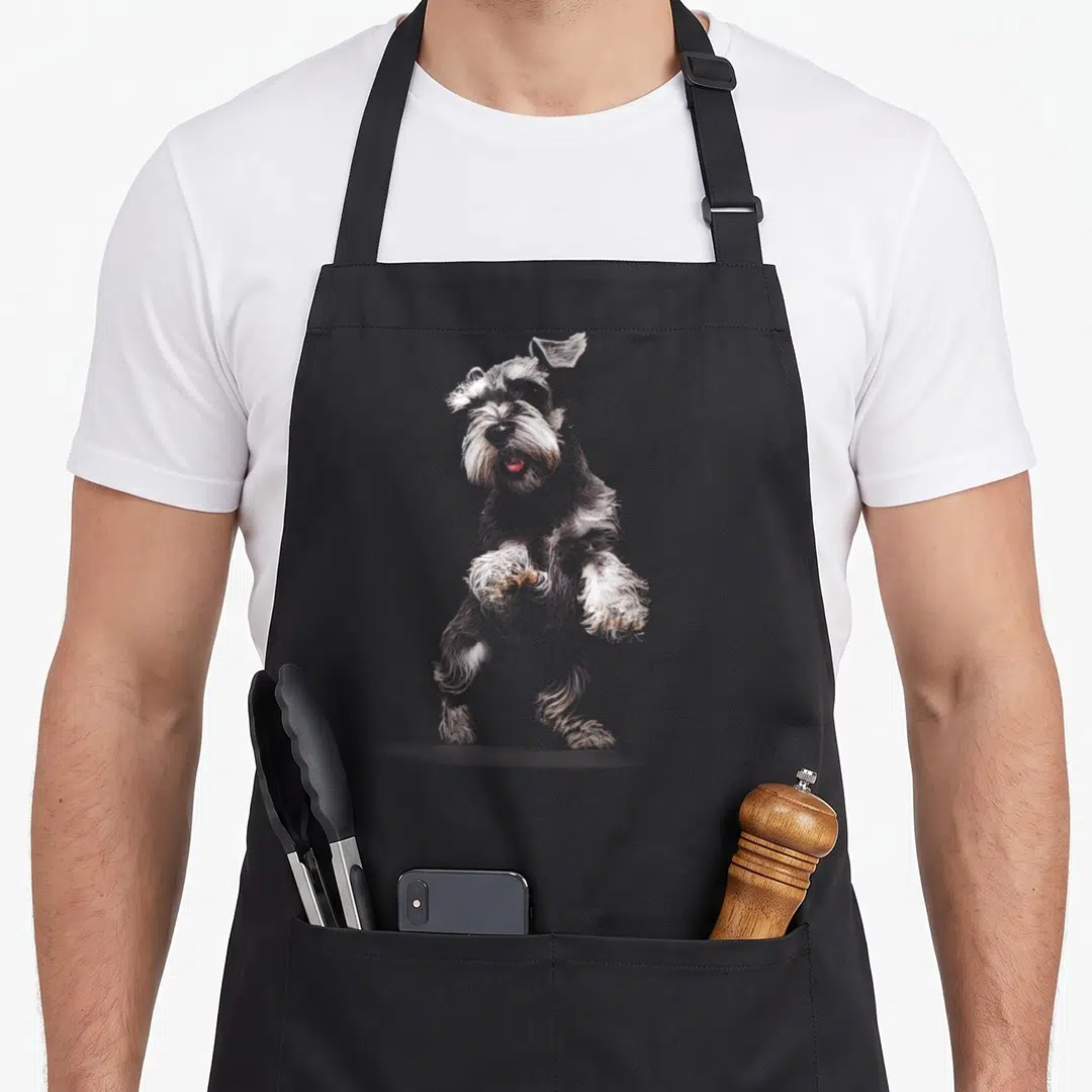 Vintage dog miniature schnauzer apron - Line art of a standing miniature schnauzer in grey, white, and brown fur — shown on a black cotton canvas apron against a white background