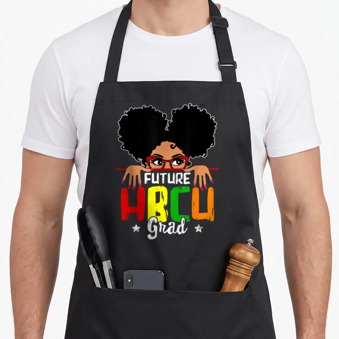 Grad student aprons - Cartoon woman with red glasses holding red line above FUTURE HBCU Grad text in black red yellow — shown on a black cotton canvas apron against a white background