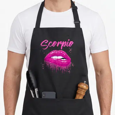 Lip birthday apron - Pink glitter text Scorpio above open lips showing white teeth — shown on a black cotton canvas apron against a white background