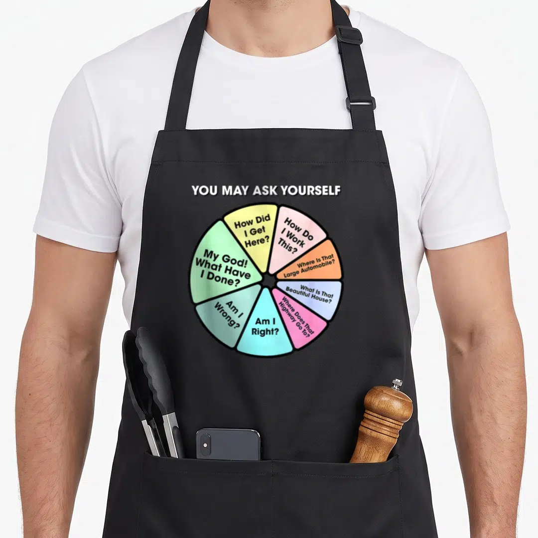 May pie apron - Multi-colored wheel with eight lyric questions and bold white header text — shown on a black cotton canvas apron against a white background
