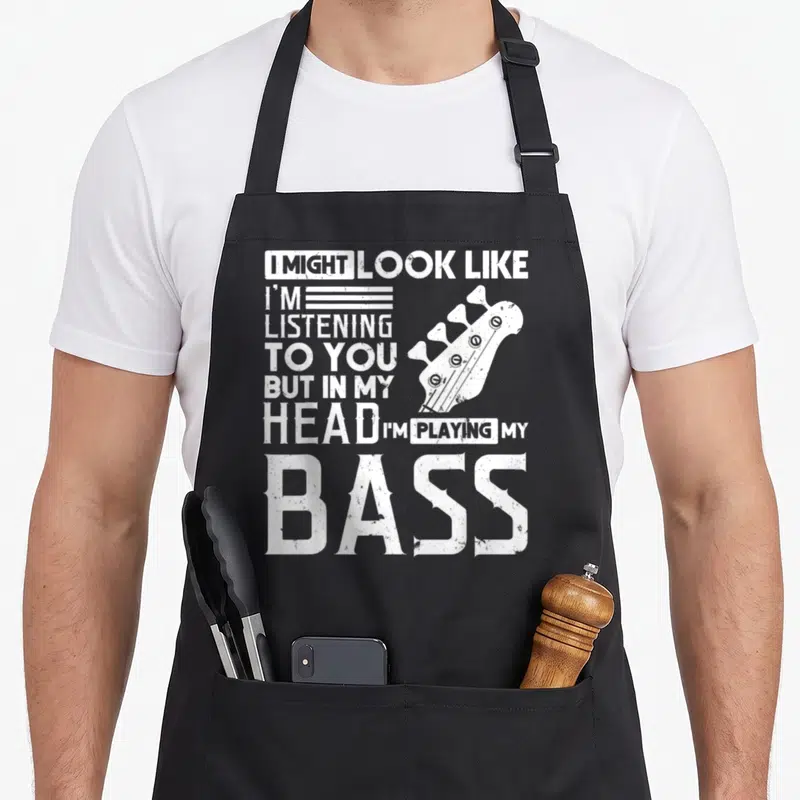 Player bassist apron - White distressed bass headstock and text reading I might look like I'm listening to you — shown on a black cotton canvas apron against a white background