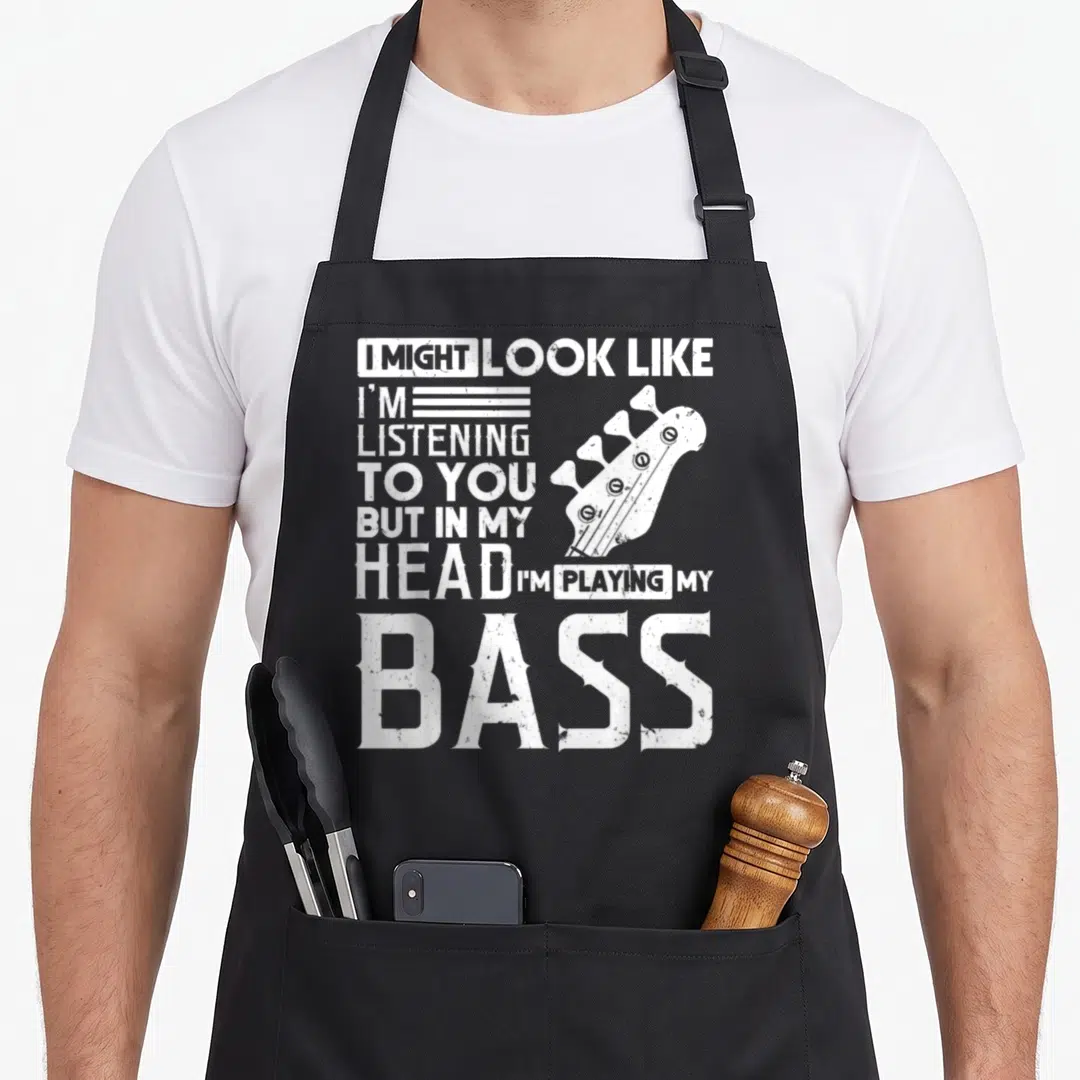 Player bassist apron - White distressed bass headstock and text reading I might look like I'm listening to you — shown on a black cotton canvas apron against a white background