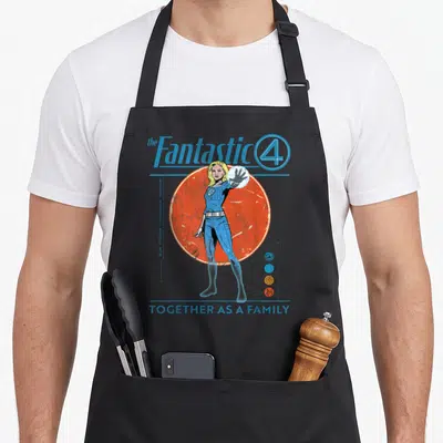 Four step apron - Sue Storm standing before orange circle with blue text reading Together As A Family — shown on a black cotton canvas apron against a white background