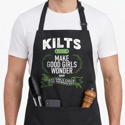 Kilt celtics apron - White stacked text with green celtic knot, laurel wreath, and ribbon banner reading about kilts — shown on a black cotton canvas apron against a white background