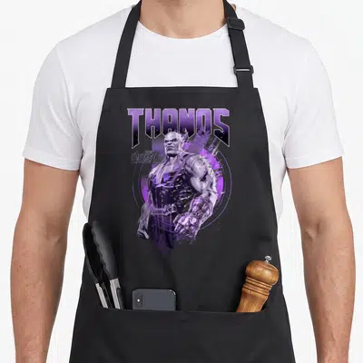 Infinity distressed apron - THANOS text above realistic purple character art inside circular graphic — shown on a black cotton canvas apron against a white background