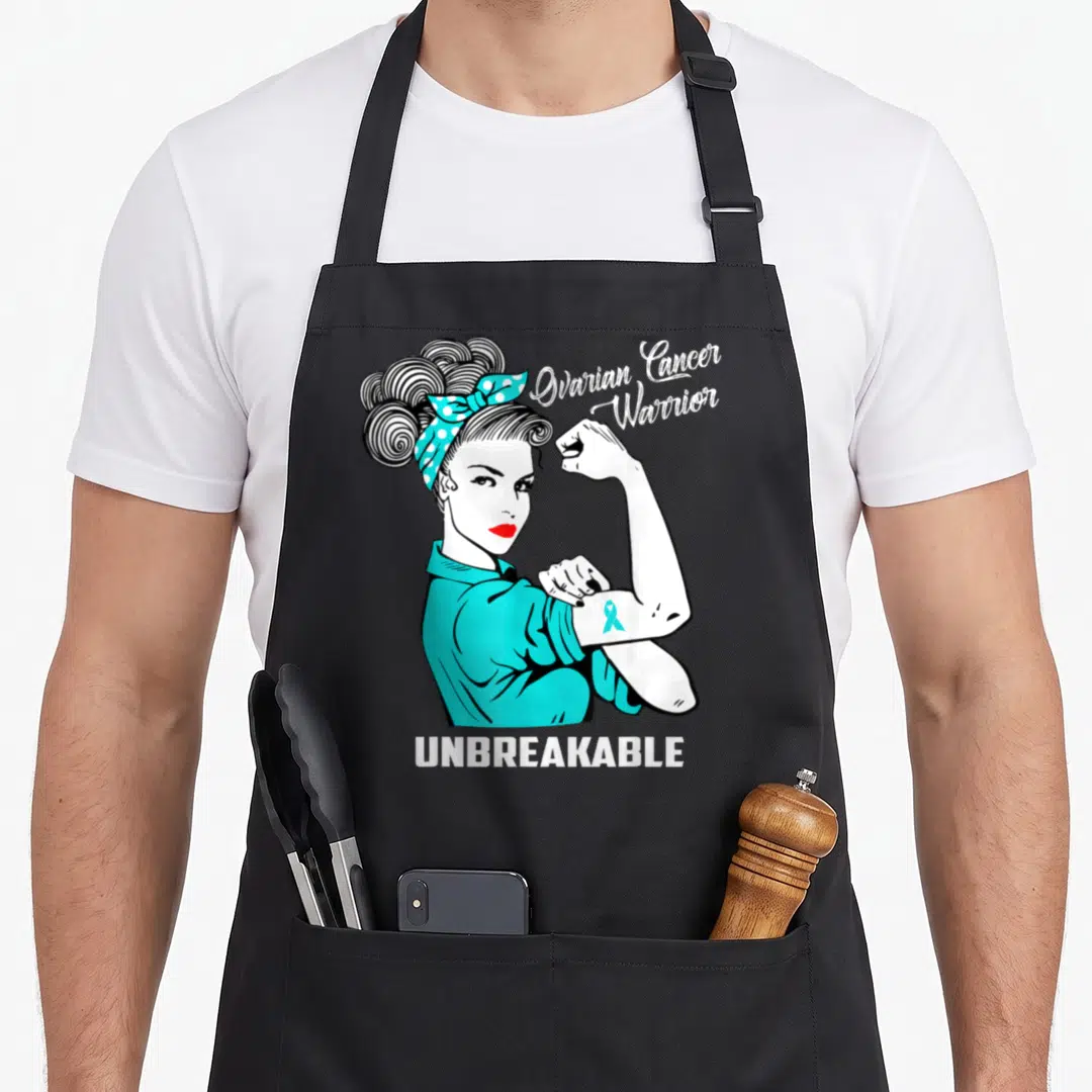 Warrior ovarian cancer awareness apron - Cartoon woman flexing arm with teal ribbon and Ovarian Cancer Warrior — shown on a black cotton canvas apron against a white background